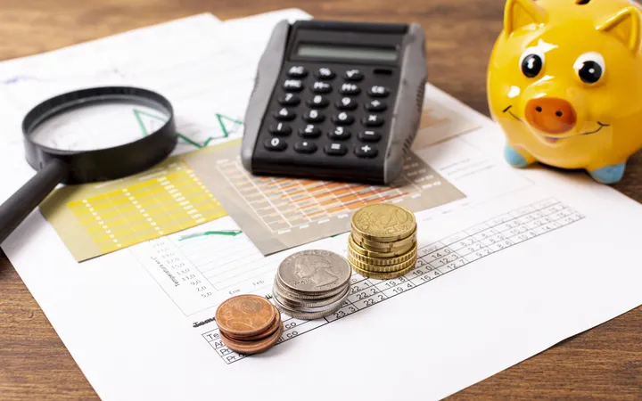 Cofre de porquinho ao lado de calculadora e material de escritório